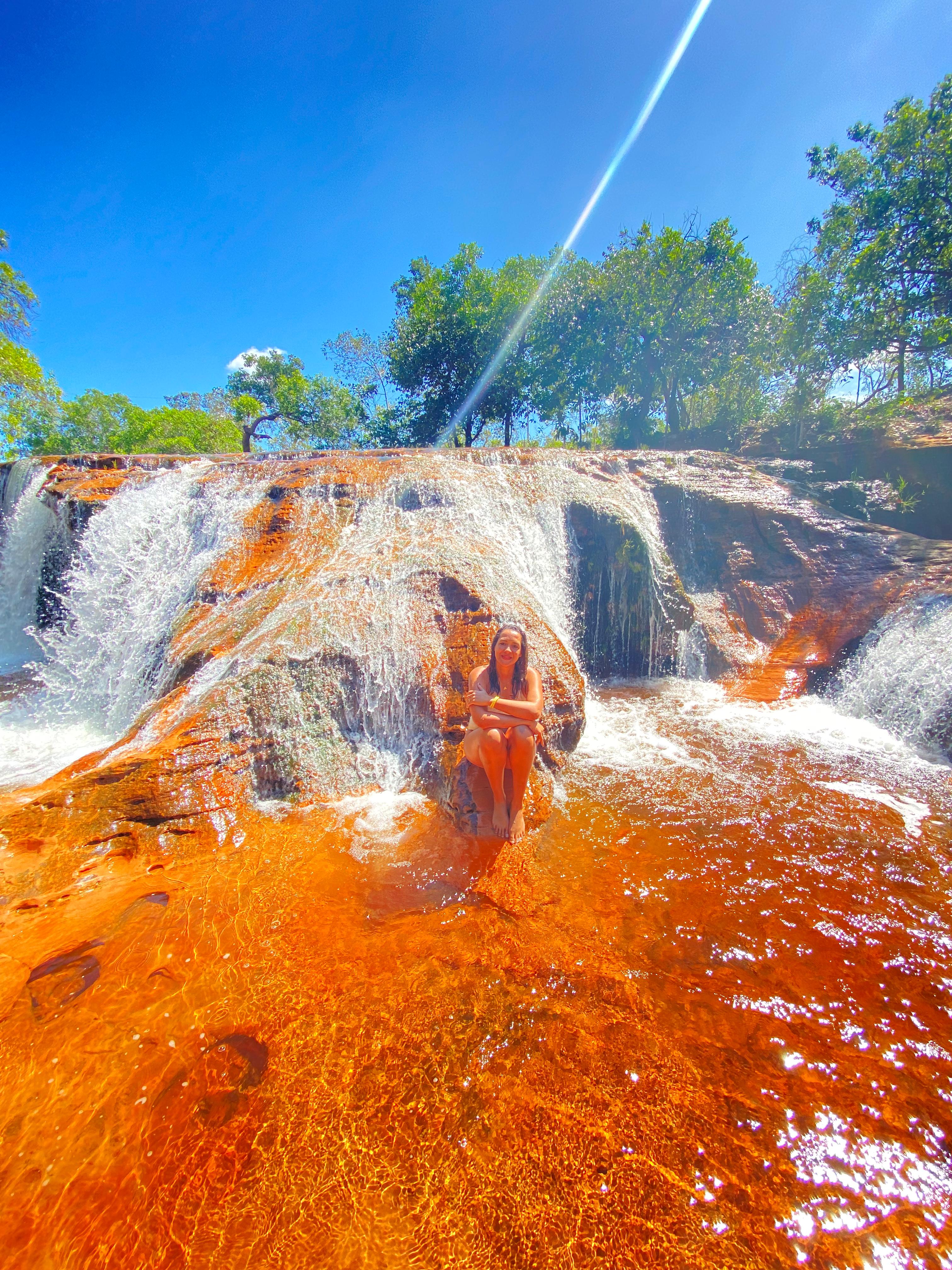 Viajante em cachoeira de águas alaranjadas